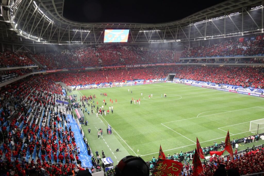Suasana pertandingan olahraga internasional dengan pemain dan penonton yang penuh semangat di stadion besar